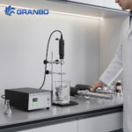 Lab technician operating a Granbo ultrasonic liquid processor on a laboratory workbench