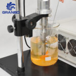Ultrasonic sonicator probe and temperature sensor submerged in liquid beaker
